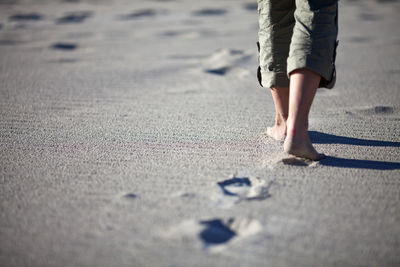 Low section of man walking on sand