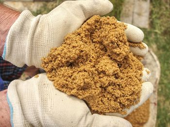 Worker hands in gloves holds sand. wet yellow sand for building, concept of traditional construction