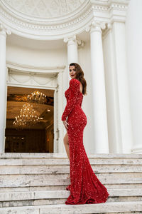 Portrait of woman with red standing against built structure