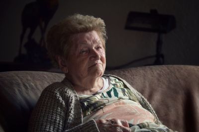 Close-up of senior woman reclining on bed at home