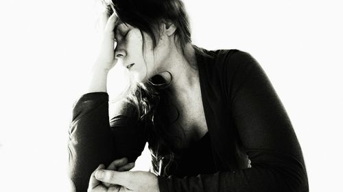 Close-up of depressed woman against white background