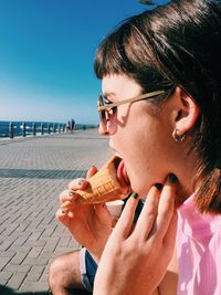 Portrait of woman eating ice cream against sky