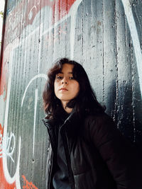 Portrait of beautiful young woman standing against wall