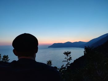 Rear view of man looking at mountains against sky