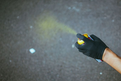 Cropped hand of person spraying on street