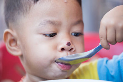 Close-up of cute boy with nose injury eating food while sitting at home