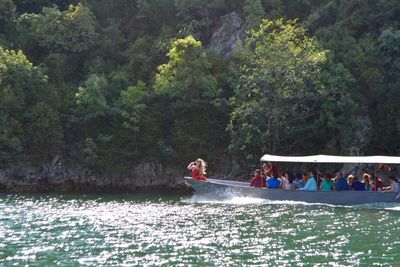 People in boat in river against mountain