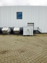 Empty chairs against white wall and house in city