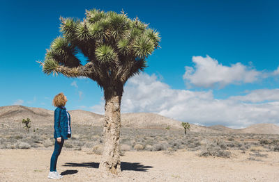 Woman standing by tree against sky