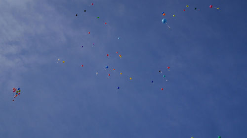 Low angle view of balloons flying against blue sky