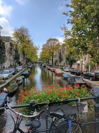 Boats in canal amidst city against sky