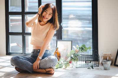 Young woman sitting on window at home