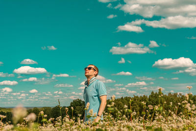 Young man standing on field against sky