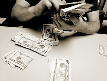 Close-up of hands holding banknotes at table