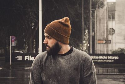 Side view of young man standing against wall