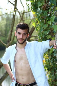 Portrait of young man standing against plants