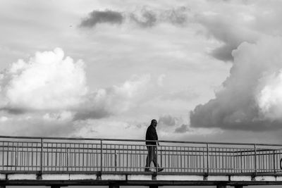 Rear view of man standing on bridge against sky