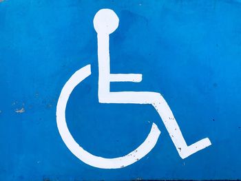 Close-up of white disabled sign on blue wall
