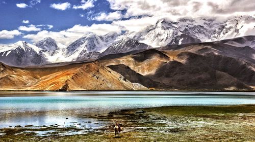 Scenic view of lake and snowcapped mountains against sky