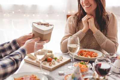 Midsection of man giving gift to woman while having food at home