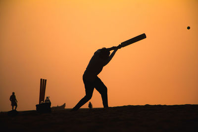 Silhouette man standing against orange sky