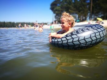 Girl swimming with inflatable ring in lake against sky