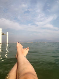 Low section of person in sea against sky