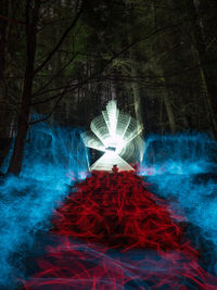Digital composite image of person in illuminated forest at night