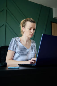 Woman working remotely at home office with laptop