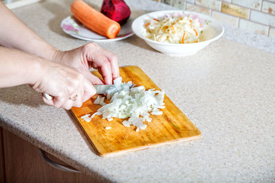Cropped hands of woman cutting vegetable in kitchen