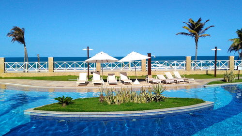 Swimming pool by sea against clear blue sky