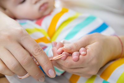 Mother cutting finger nails of baby at home