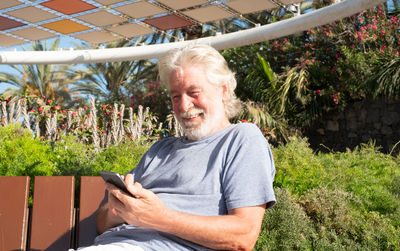 Smiling senior man using smart phone while sitting in park