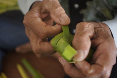Cropped hands making craft product with bamboo leaves