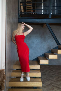 Portrait of young woman standing against wall