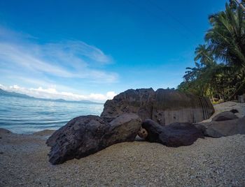 Rocks on beach against blue sky