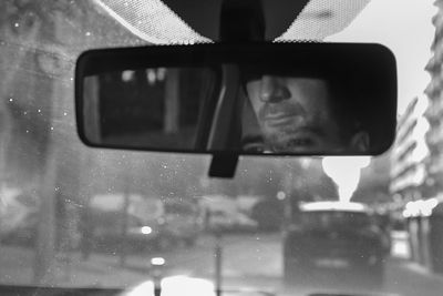 Double exposure of man reflecting on rear-view mirror