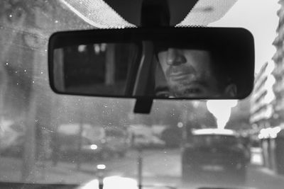 Double exposure of man reflecting on rear-view mirror