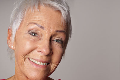 Portrait of happy senior woman against gray background