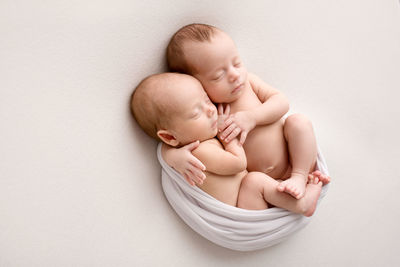 Portrait of cute baby boy lying on white background