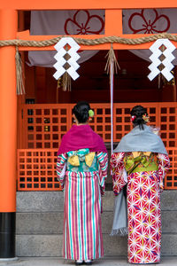 Rear view of friends hanging outside temple