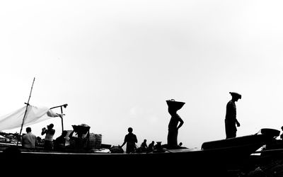 Silhouette people on boat against clear sky
