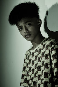 Portrait of boy standing against gray background