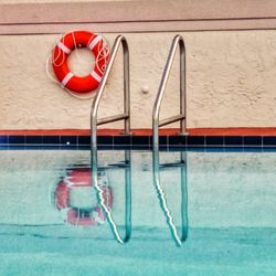 Reflection of railings and life belt on swimming pool