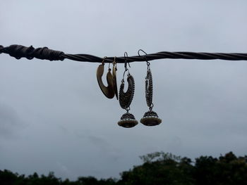 Low angle view of earring hanging on string against sky