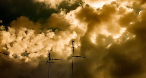 Low angle view of power lines against cloudy sky