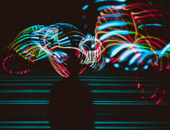 Silhouette man standing against illuminated colorful light painting