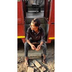 Full length of man sitting on door of train