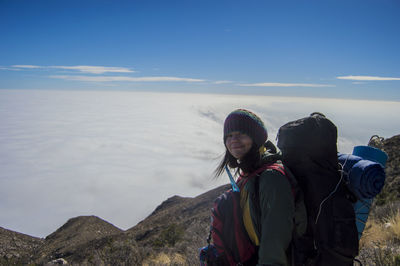 Woman standing on rock against cloudscape