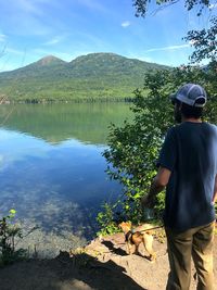 Rear view of man standing by lake against sky